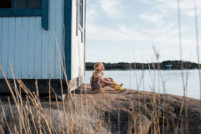 Young girl sat on a rock at the beach using her imagination playing