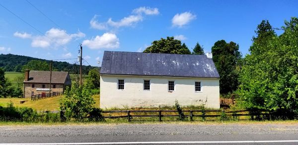 Houses by trees and buildings against blue sky