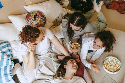 Directly above shot of female friends having snacks while spending leisure time at home