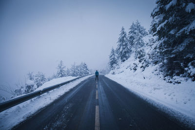 Road amidst snow covered trees against sky