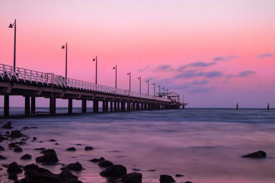 Pier over sea against sky during sunset