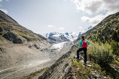 Rear view of hiker on mountain against sky