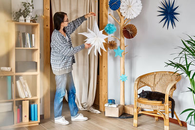 Decoration for the winter holidays. woman decorating home with stars, fans and snowflakes