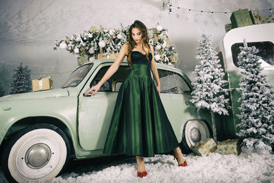 A charming girl is happy about the new year and poses on the ice rink dressing up a christmas tree