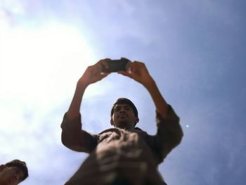 Low angle view of man with arms raised against sky