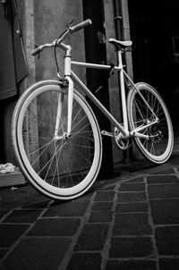 Bicycle parked on footpath by wall