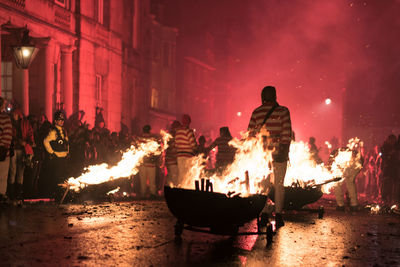People around bonfire in city at night during festival