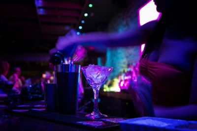 Midsection of sensuous bartender pouring drink in glass at bar counter