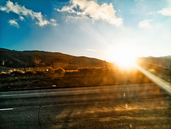 Road by mountains against sky during sunset