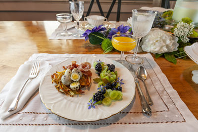 Quail eggs on a hashbrown potato nest with prosciutto and decorative fruit.