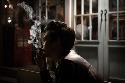 Portrait of young man drinking glass window