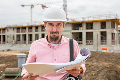 Portrait of man holding camera at construction site