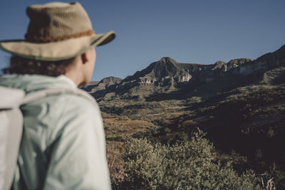 Low angle view of woman standing on mountain against clear sky