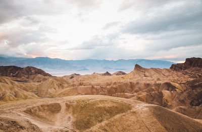 Scenic view of desert against cloudy sky