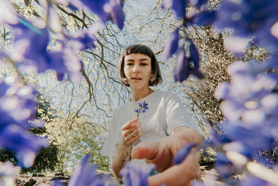 Portrait of woman with pink flowers against trees