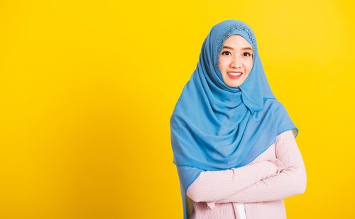 Portrait of a smiling young woman against yellow background