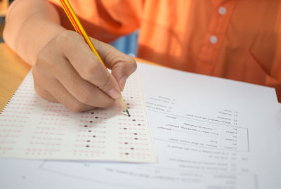 Midsection of man holding paper with text on table