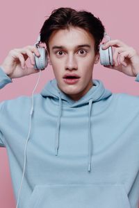 Portrait of man with headphones against pink background
