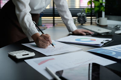 Midsection of business people working on table