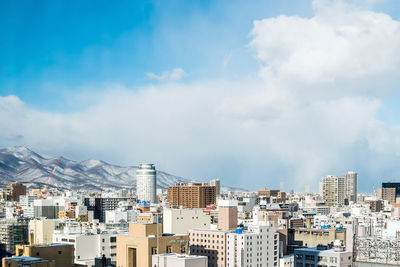 Cityscape and snowcapped mountain against sky