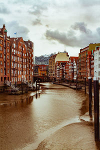 Canal amidst buildings in city against sky