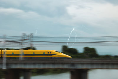 Train on bridge over river against sky