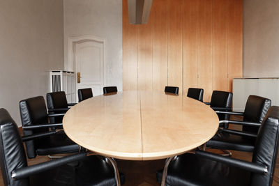 Empty chairs by conference table in office