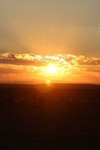 Scenic view of silhouette landscape against orange sky