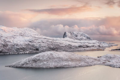 Scenic view of mountains by sea against sky during sunset