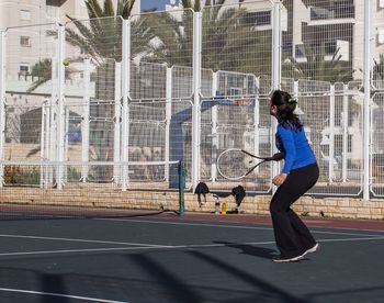 Side view woman playing tennis on court during sunny day