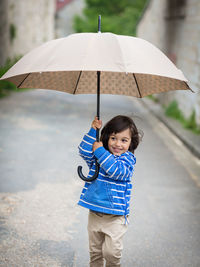 Little eastern handsome baby boy playing with umbrella outdoor