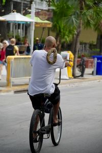 Rear view of man riding bicycle on street