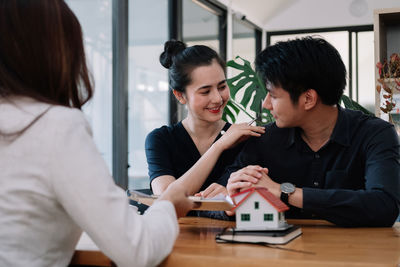 Side view of businesswoman using mobile phone while sitting on table