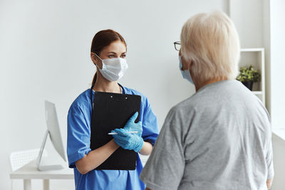 Side view of young woman holding dentures while standing against white background