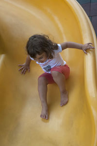 Full length of cute girl sliding on slide at playground