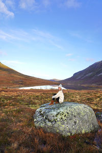 Rear view of man standing on rock against sky