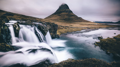 Kirkjufell mountain and waterfall against sky