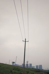 Low angle view of electricity pylon on field against sky