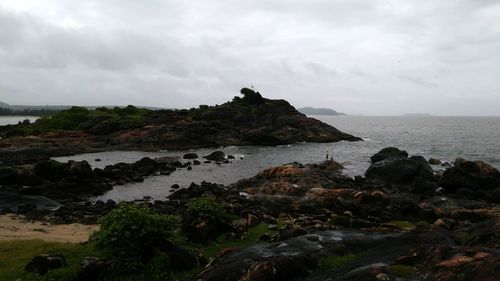 Rock formation by sea against sky