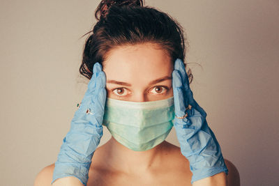 Portrait of young woman covering face against wall