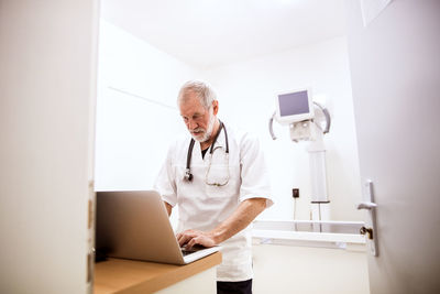 Senior vet using laptop in clinic