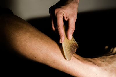 Cropped hand of massage therapist massaging human leg