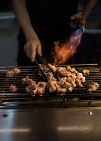 Close-up of man preparing food on barbecue grill