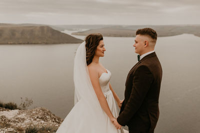 Portrait of smiling couple standing against sky