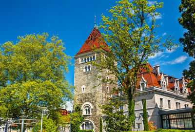 Low angle view of clock tower amidst trees and buildings against sky