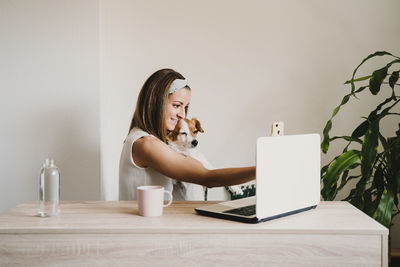 Woman using phone while sitting on table