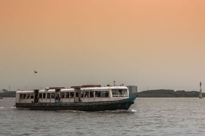 Boat sailing on sea against clear sky during sunset