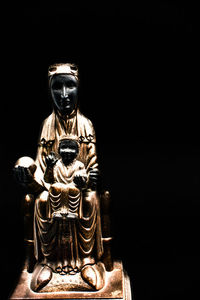 Close-up of buddha statue against black background