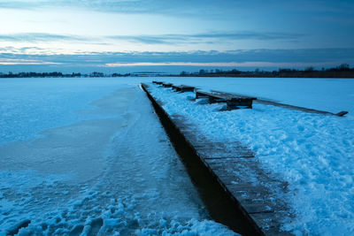 Wooden pier covered with snow and the evening sky