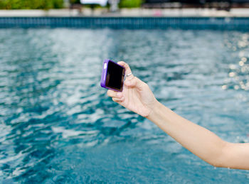 Cropped hand of woman taking selfie in swimming pool